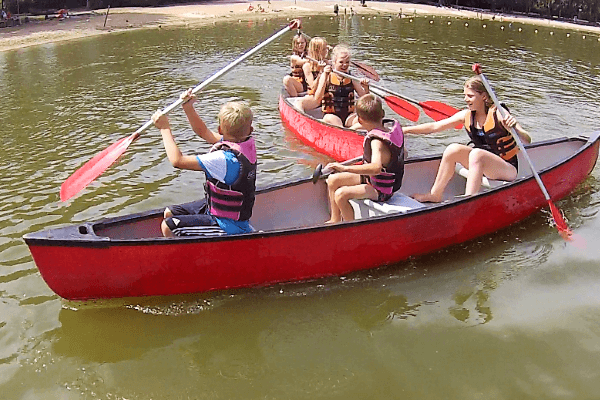 Kinder fahren im Kanu über den See