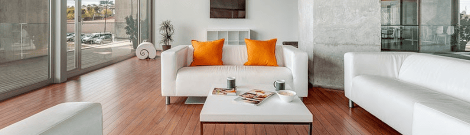Eine Lounge mit einer weißen Couch und orangenen Kissen