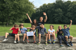 Kindergruppe sitzt auf Baumstamm