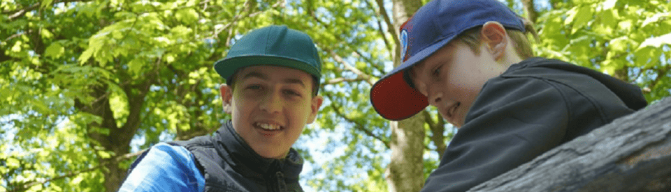 Jungs sitzen auf Baumstamm und lachen
