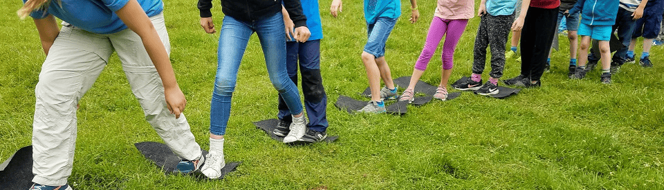 Kinder spielen auf Wiese Kooperationsspiel