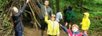 Kinder stehen vor Holzunterschlupf