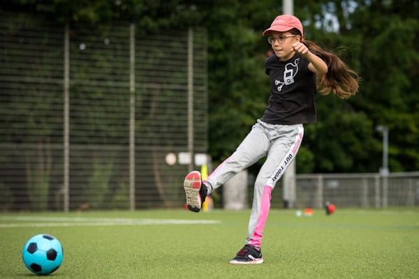 Mädchen schießt Ball im Fußballcamp für Mädchen