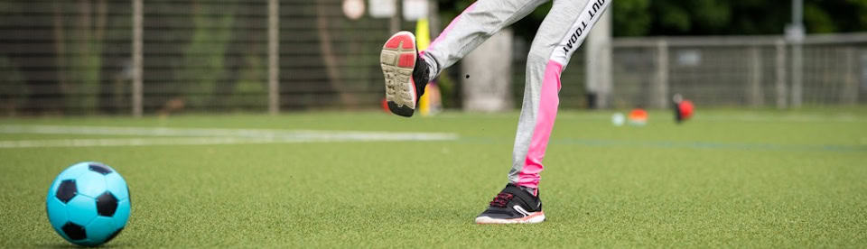 Mädchen schießt Ball im Fußballcamp für Mädchen