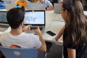 Junge und Mädchen schauen auf Computer im Tagescamp Film-Making