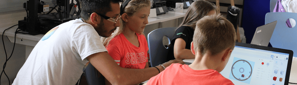 Kinder mit einem Lehrer vor einem Laptop