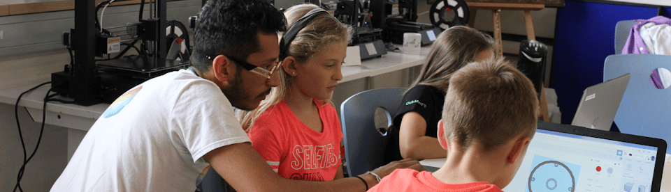 Betreuer und Kinder vorm Laptop
