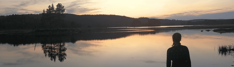 Mädchen beobachtet Sonnenuntergang an See