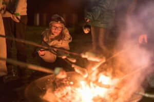 Kinder grillen Stockbrot über dem Lagerfeuer