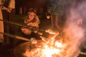 Kinder grillen Stockbrot über dem Lagerfeuer