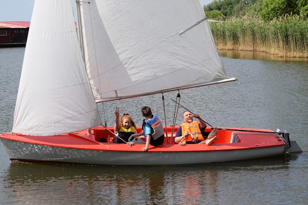 Kinder fahren mit einem Segelboot über einen See