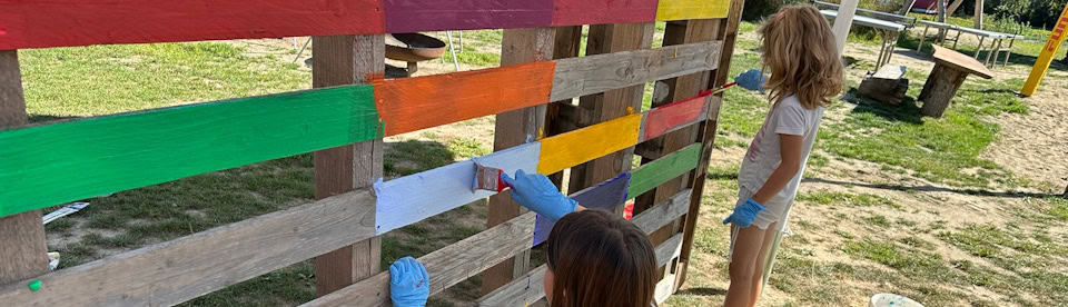 Kinder beim Streichen eines Zaunes