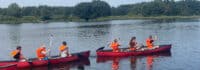 Kinder fahren Kanu im Feriencamp