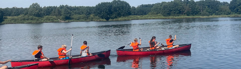 Kinder fahren Kanu im Feriencamp
