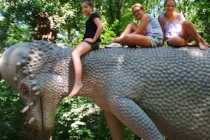 Drei Mädchen auf einem Dinosaurierrücken im Abenteuercamp Bautzen