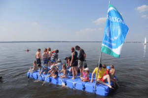 Kindergruppe auf selbstgebautem Floß