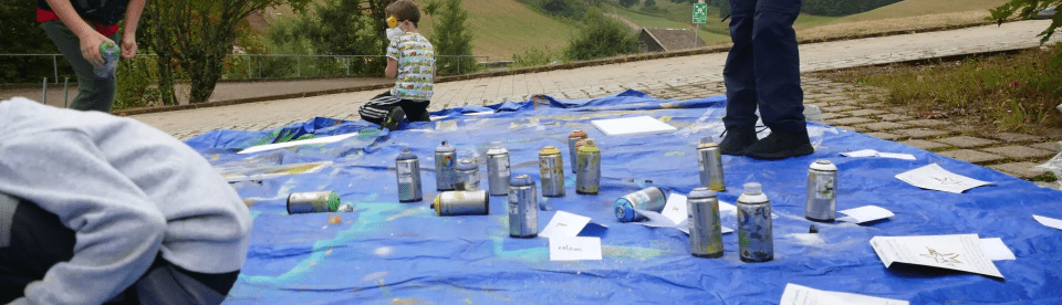 Kinder sprühen Farbe auf blauer Plane
