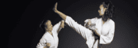 Ein Mädchen macht einen Highkick, welcher von einem anderen abgehwehrt wird