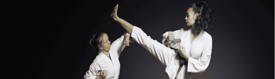 Ein Mädchen macht einen Highkick, welcher von einem anderen abgehwehrt wird