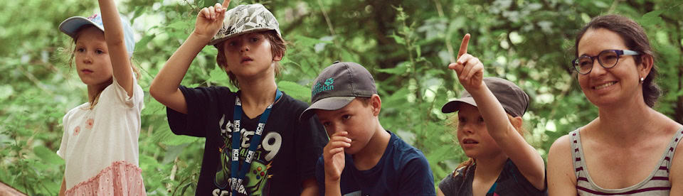 Kinder sitzen im Wald auf einem Baumstamm