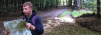 Ein Junge mit einer Landkarte auf einem Waldweg