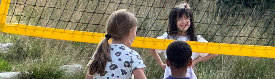 Kinder auf einem Beachvolleyballfeld