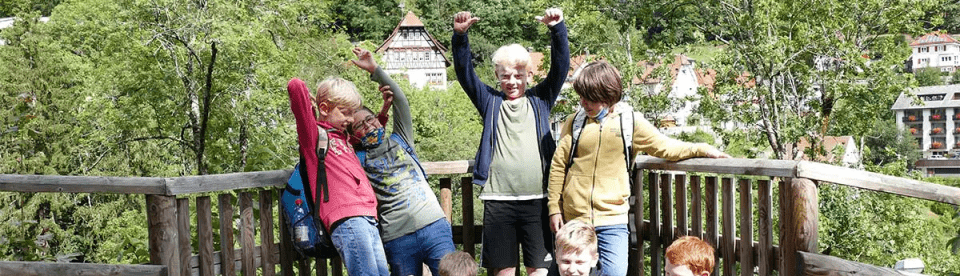 Gruppenbild glückliche Kindern vorm Holzgeländer