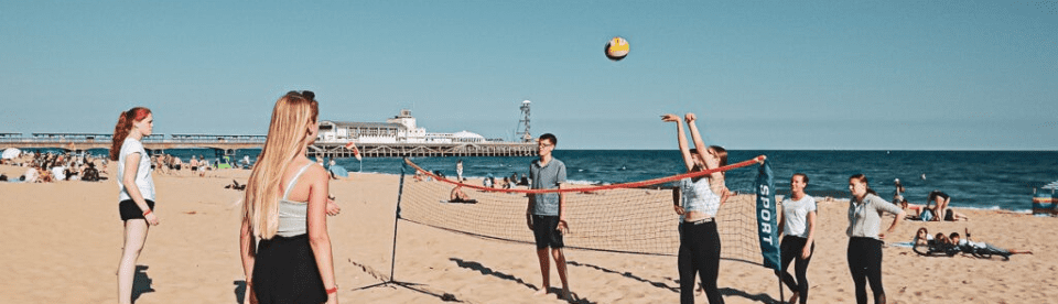 Jugendliche spielen Beachvolleyball am Strand