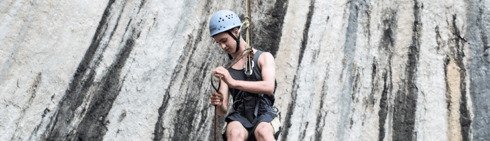 Slider Junge hängt in Klettergeschirr