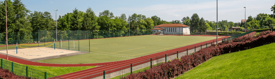 Ein Fußballplatz umzogen von einer Tartanbahn und ein Beach-Volleyballfeld