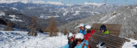 Kinder in Skisachen auf Bank im Schnee