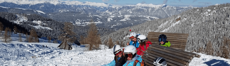 Kinder in Skisachen auf Bank im Schnee