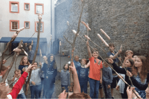 Kinder mit Stockbrot vor Burg
