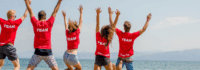 Teamer die vor dem Meer springen