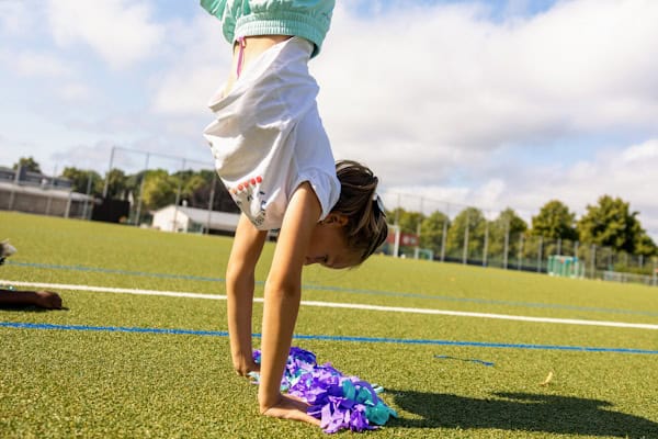 Mädchen macht auf einem Fußballplatz einen Handstand