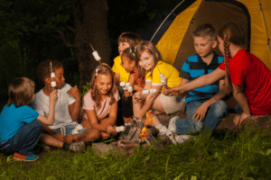 Kinder sitzen am Lagerfeuer