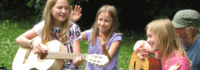 Gruppe von Mädchen beim Singen mit Gitarre