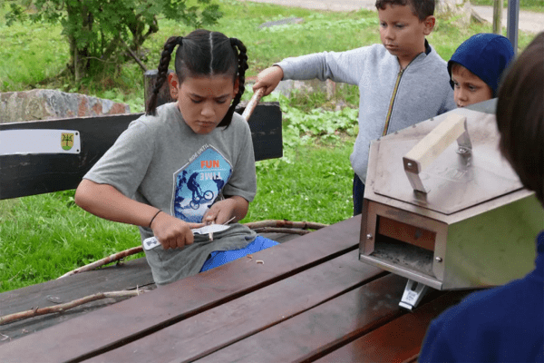 Junge beim Schnitzen im Englisch-Outdoorcamp