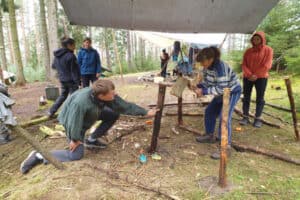 Jugendliche befinden sich in einem Camp im Waldcamp Thüringen und bauen am Lager