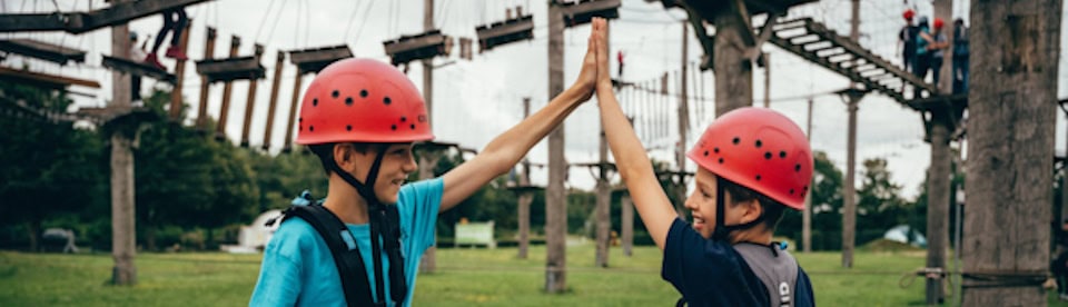 Zwei Jungs klatschen sich ab im Hochseilgarten