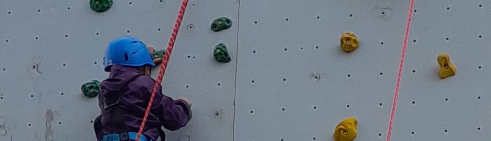 Kind klettert an Kletterwand