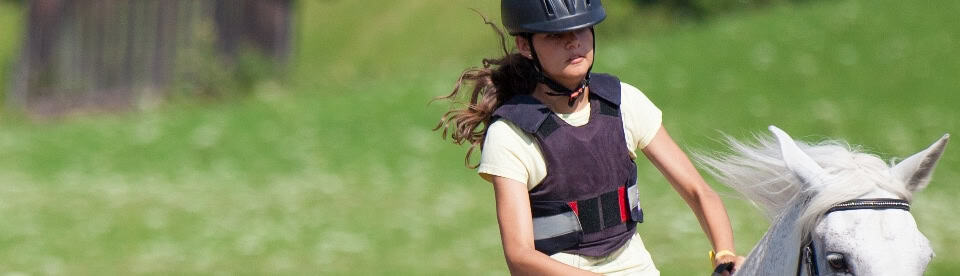 Mädchen galoppiert auf weißem Pony