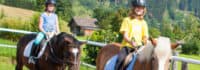 Kinder reiten in der Gruppe auf dem Platz