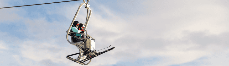 Zwei Personen fahren mit dem Skilift