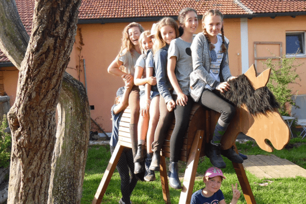 fünf Mädchen auf Holzpferd