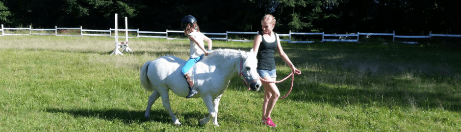 Mädchen wird auf Pony geführt