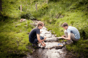 Zwei Jungs an einem Bach im Wildniscamp