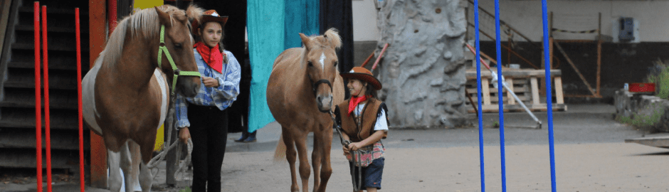 zwei Mädchen mit Pferden in Kostüm