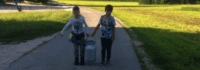 Zwei Jungen tragen große Milchkanne