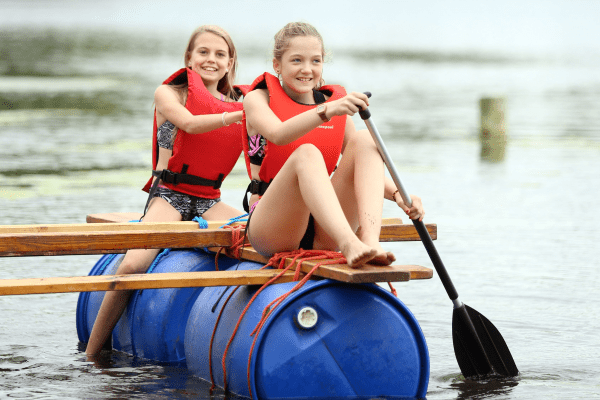 Zwei Mädchen auf Tonne im Wasser